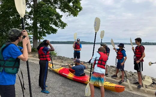 a group of people standing next to kayaks on a beach