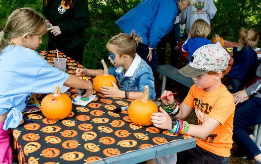a group of children sitting around a table with pumpkins