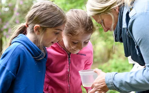 a group of people looking at a small girl holding a cup