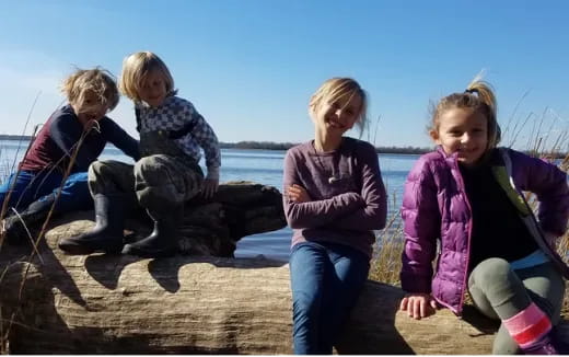 a group of children sitting on a rock by the water