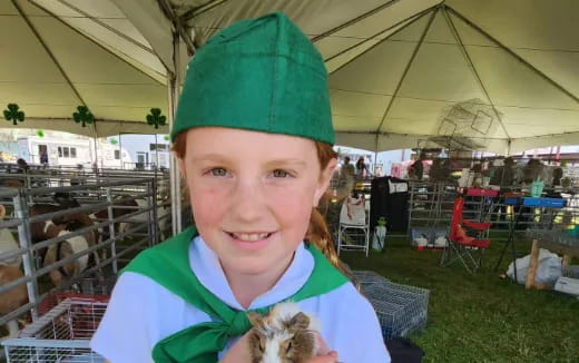 a girl wearing a green hat and holding a small animal