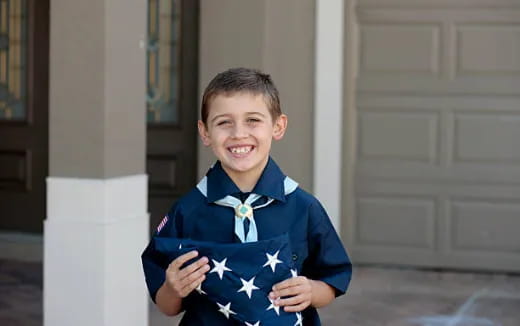 a boy in a blue shirt and bow tie holding a flag