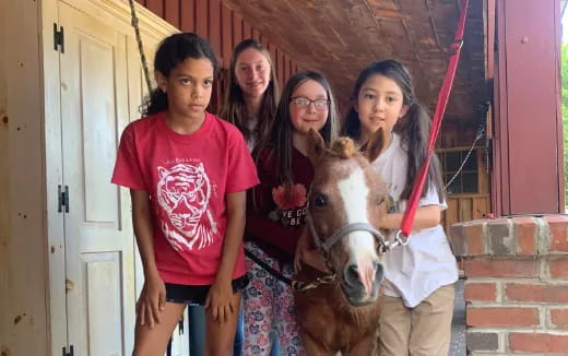 a group of girls posing with a horse