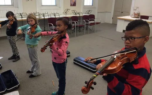 a person playing a violin with a group of children