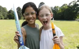 a couple of girls holding baseball bats