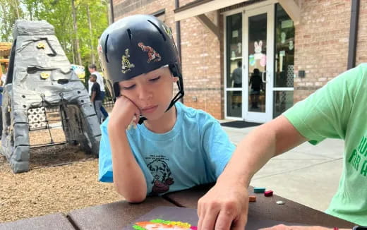 a person and a boy sitting at a table outside