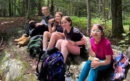 a group of people sitting on a rock in the woods