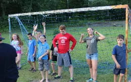 a group of kids standing in a grassy area with a person in a red shirt and a white