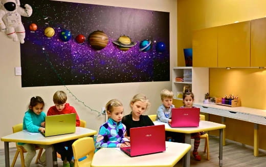 a group of children sitting at desks with laptops