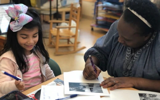 a woman and a girl writing on paper