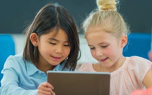 a couple of children looking at a laptop