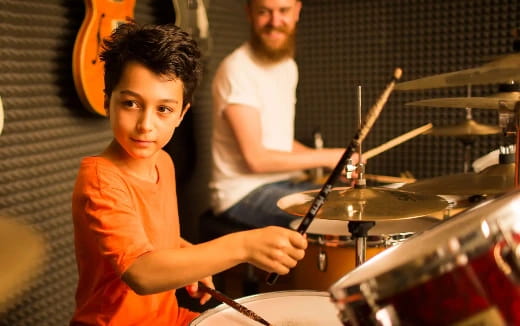 a person and a boy playing drums