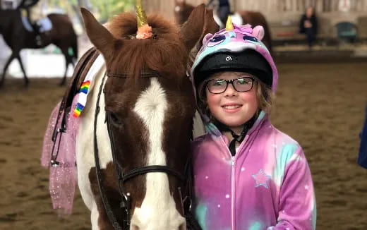 a girl standing next to a horse