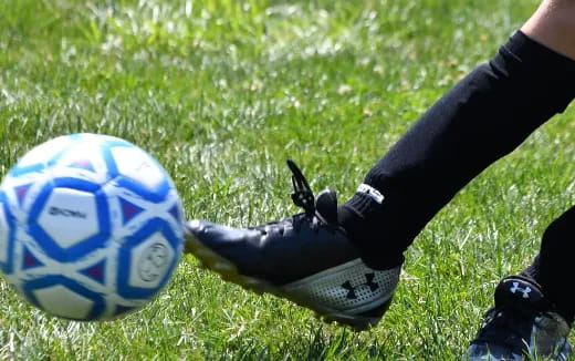 a person's feet and a football ball on grass