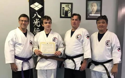a group of men in white karate uniforms holding a certificate