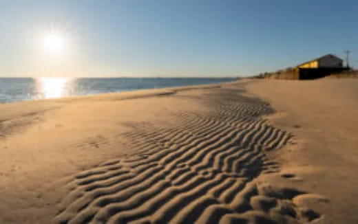 a sandy beach with the sun setting