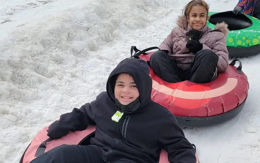 a couple of kids in a sled in the snow