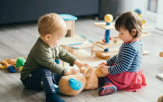 a couple of children playing with a stuffed animal
