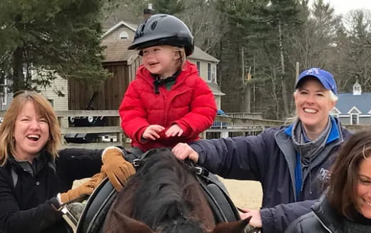 a woman riding a horse with a child on her back