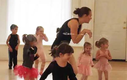 a person and a group of children dancing in a room