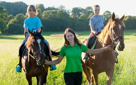 a person leading a group of children on horses