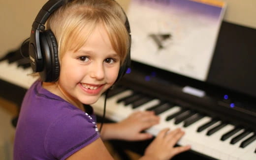 a girl wearing headphones and playing a piano