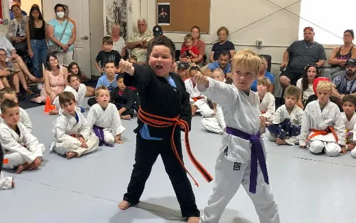 a person and a boy in karate uniforms with a crowd watching