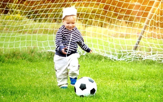 a young boy playing with a football ball