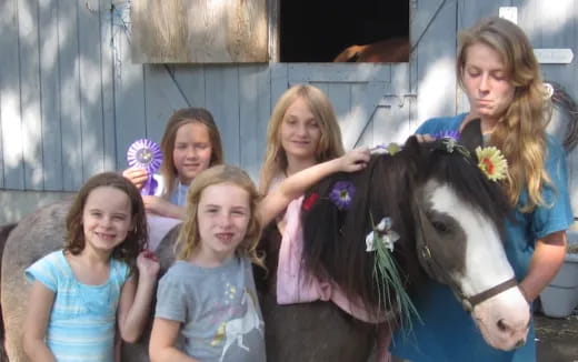 a group of girls stand around a horse