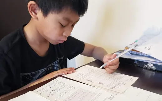 a young boy writing on a book