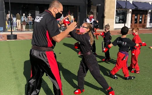 a man and a woman dancing with kids on a field