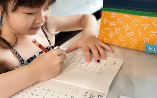 a young girl writing on a piece of paper