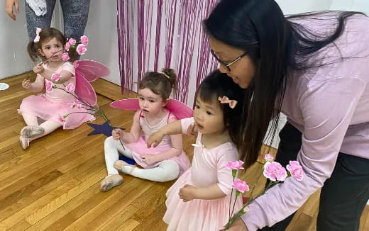 a person kneeling next to a group of girls sitting on the floor