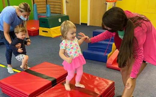 a person and children playing on a mat