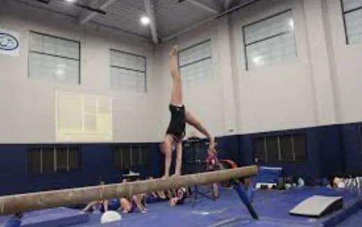 a person doing a handstand on a mat in a gym