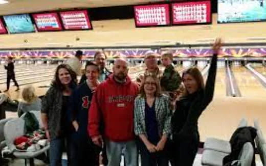 a group of people posing for a photo in a bowling alley