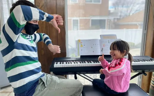 a person and a girl playing piano