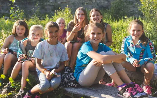 a group of girls sitting on a rock posing for the camera