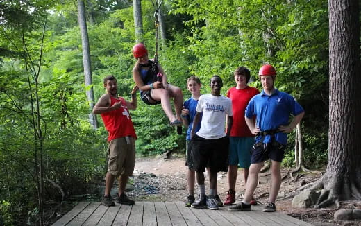 a group of people standing on a wooden platform in the woods