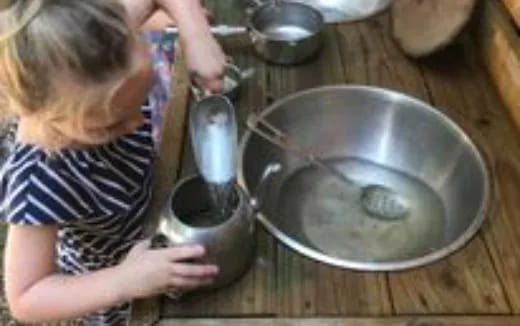 a child pouring a liquid into a pot