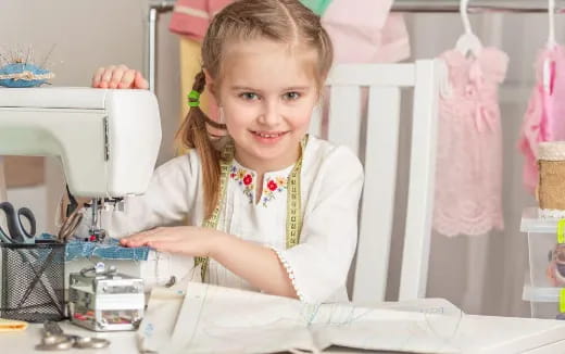 a young girl sitting at a sewing machine