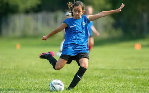 a girl kicking a football ball