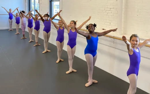 a group of girls in blue and purple uniforms dancing on a concrete floor