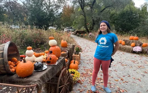 a girl standing next to a table with pumpkins on it