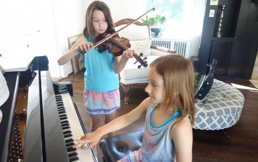 a girl playing the violin next to a girl playing the piano