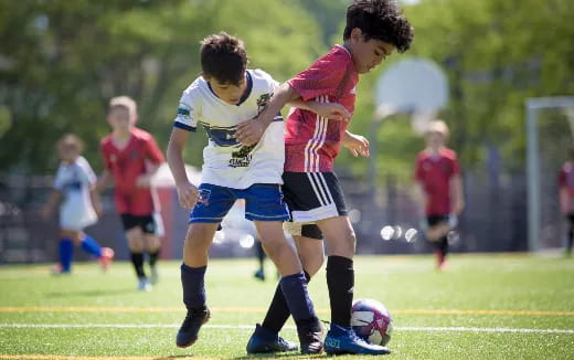 a group of kids compete over a football ball