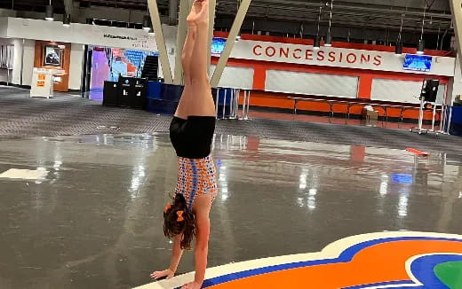 a person doing a handstand on a mat in a gymnasium