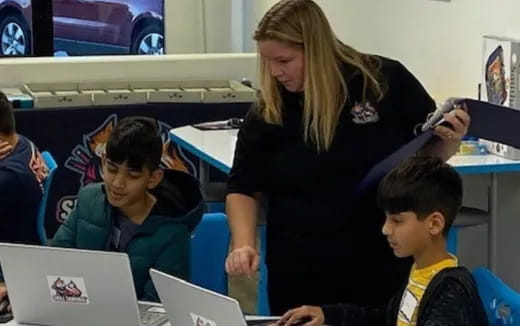 a person and several kids using laptops