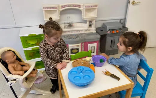 a group of children sitting at a table with food and toys