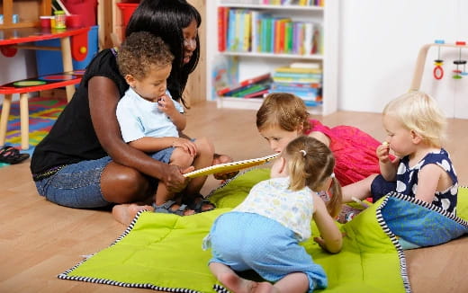 a person and several children sitting on a blanket